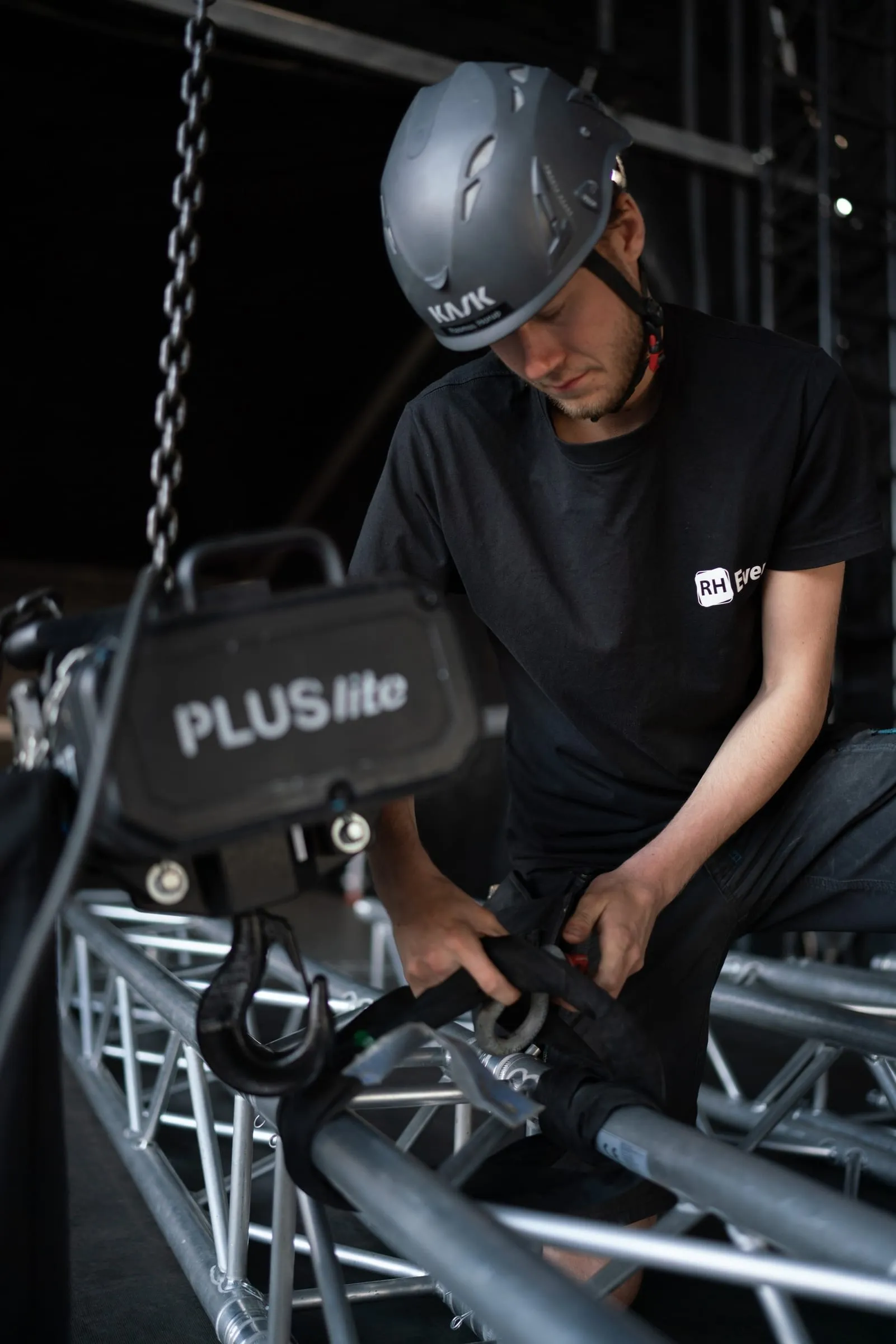 Rigger fra RH Event sætter en kædetalje på truss'en over scenen