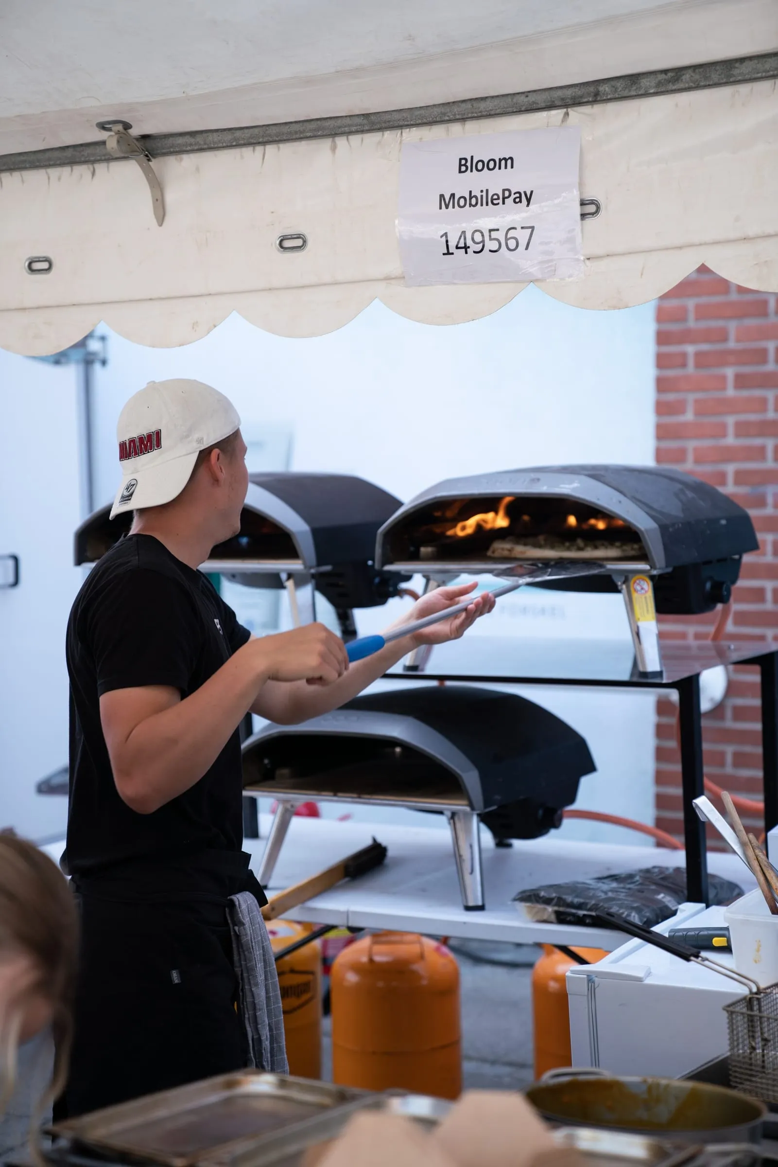 Kok skyder en pizza ind i den brændende ovn i madboden