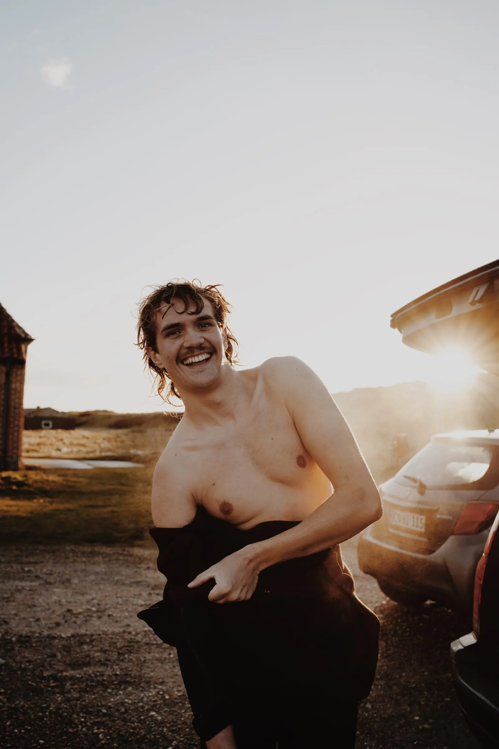Surferen griner med håndklædet om livet foran den åbne bagklap