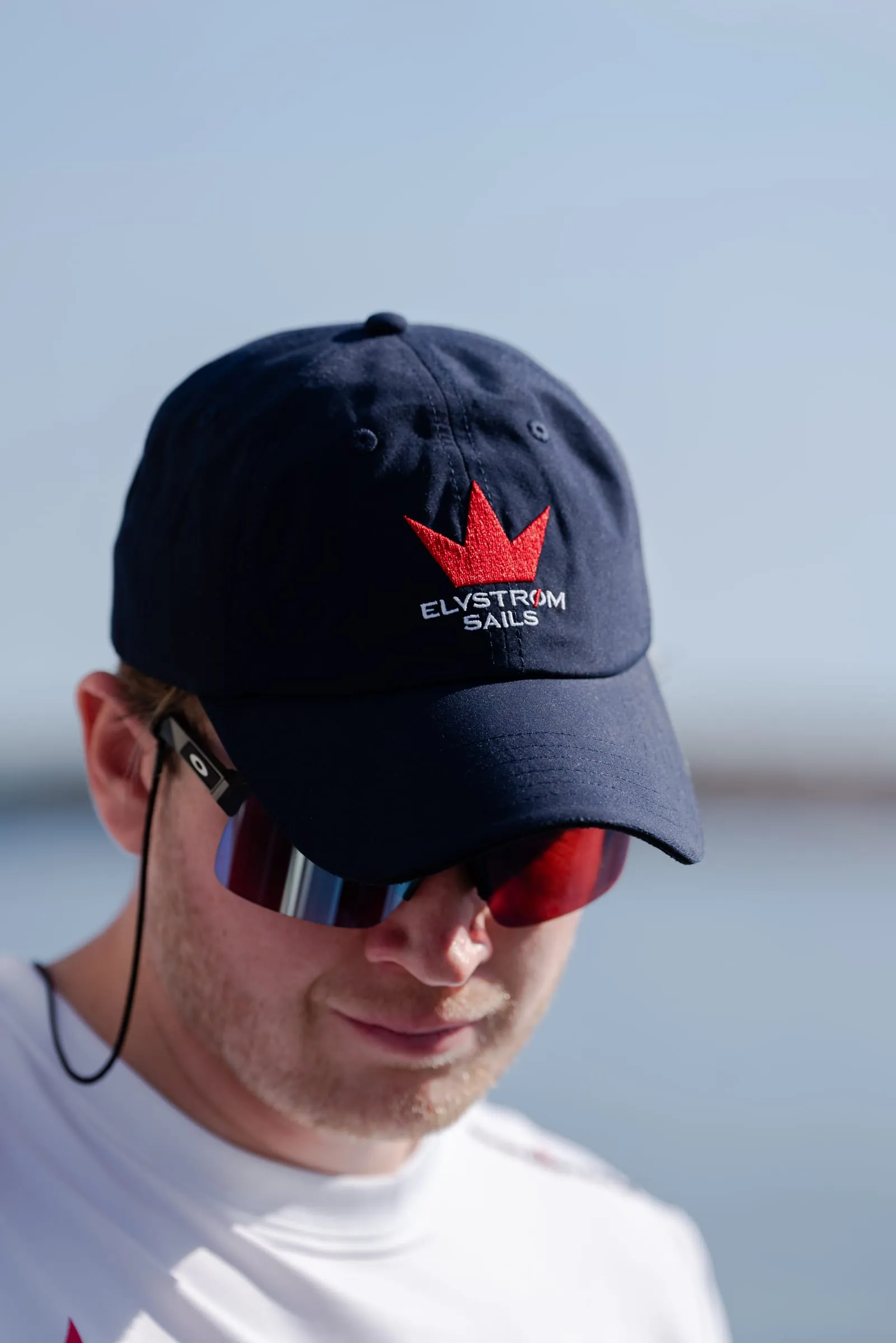 Sejler i navyblå Elvstrøm Sails-cap og solbriller på havnen
