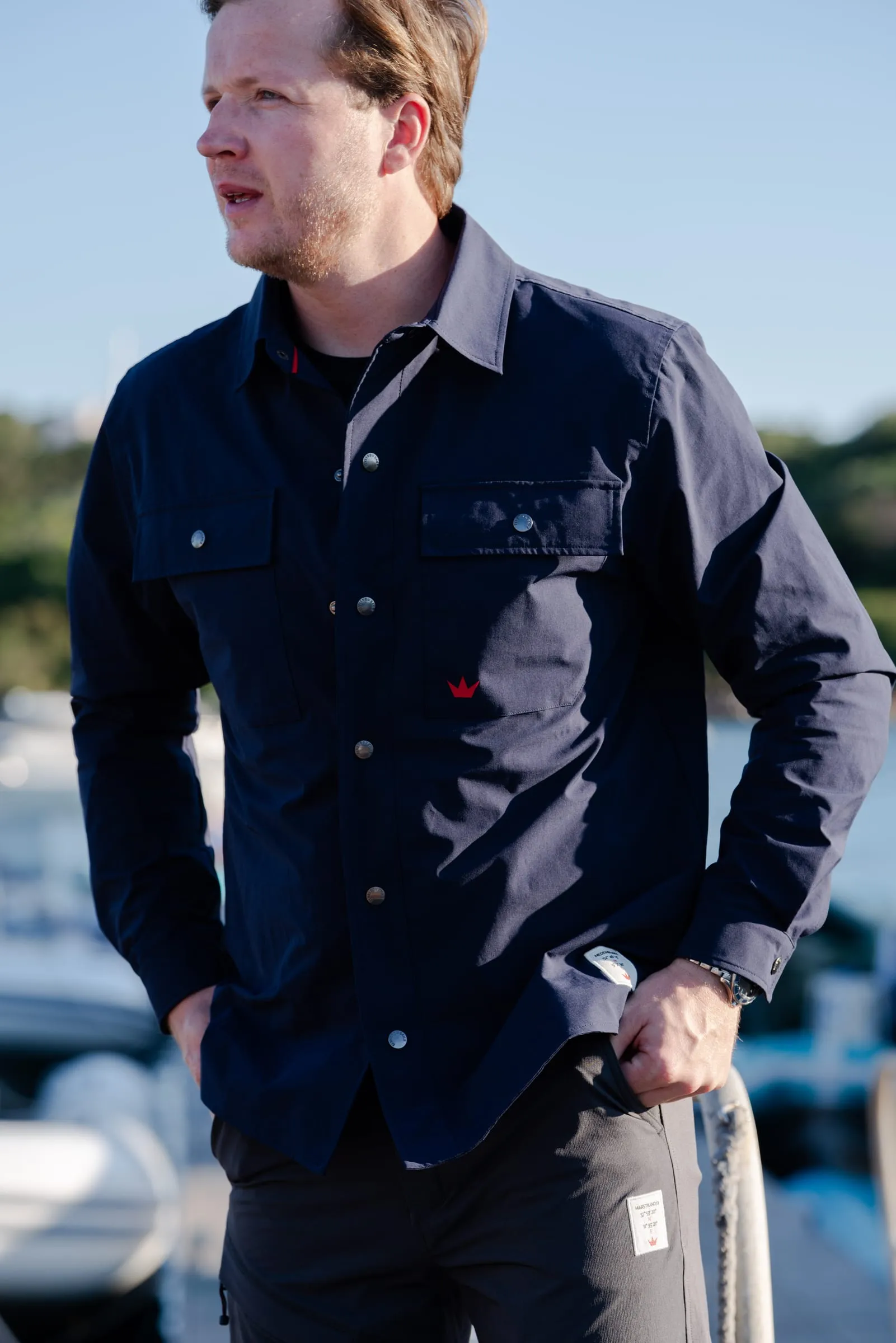 Model i navyblå overshirt med sejlpose foran lystbådehavnen