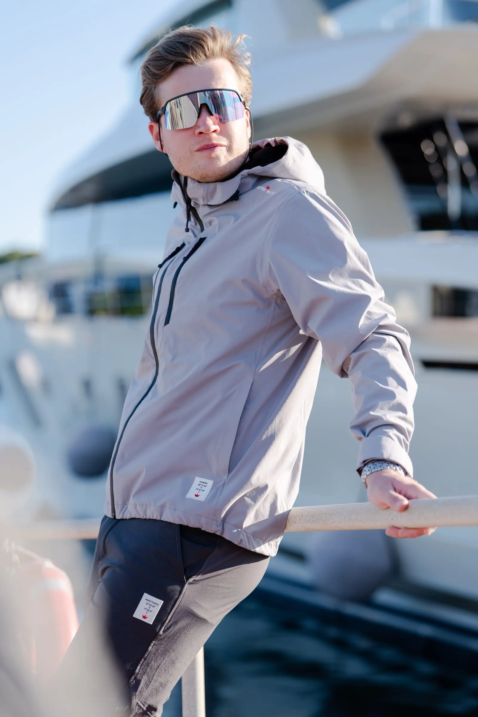 Model i grå sejlerjakke og solbriller på flydebroen